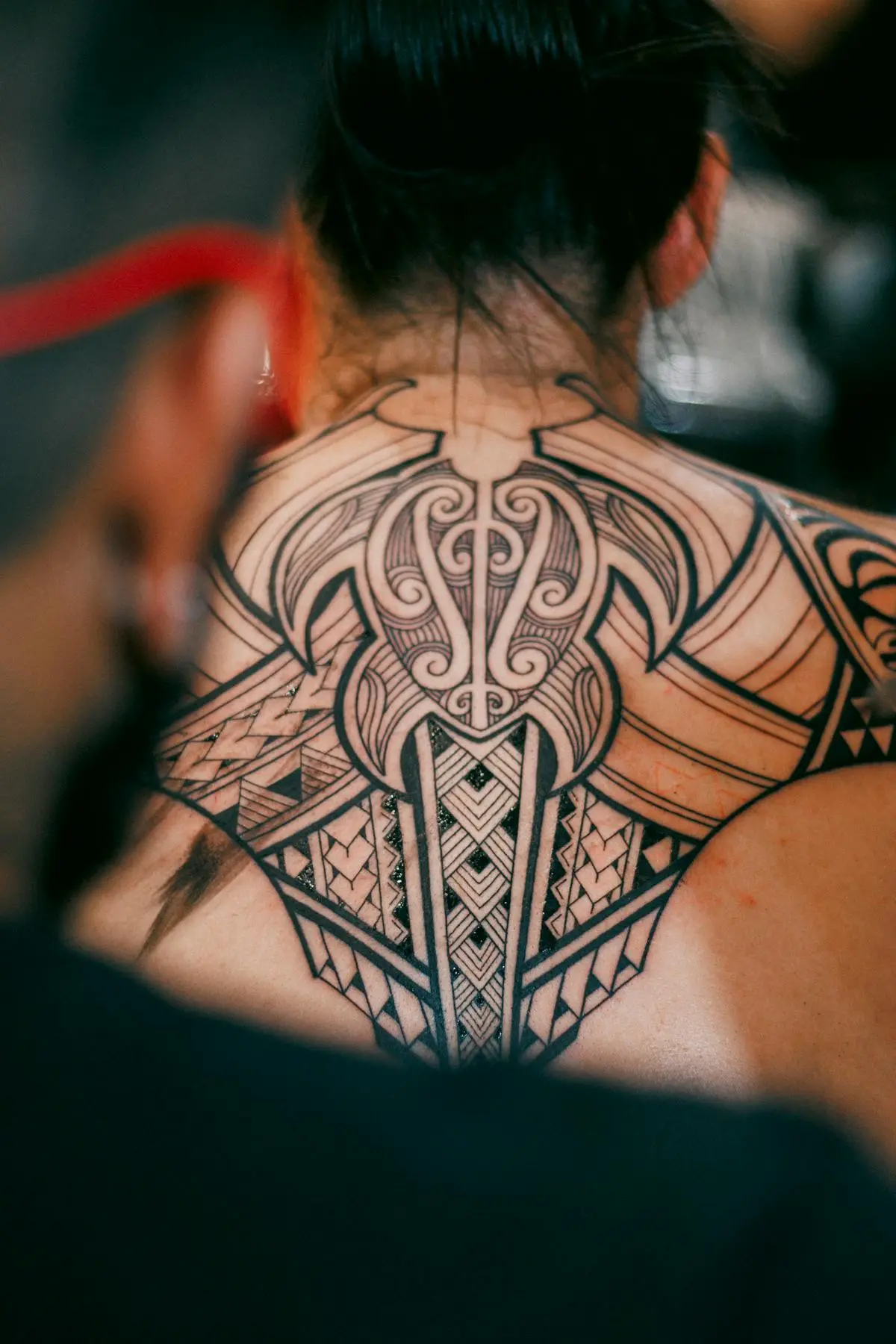 Heavy solid-black ornamental blackwork covering the back of the neck and upper back