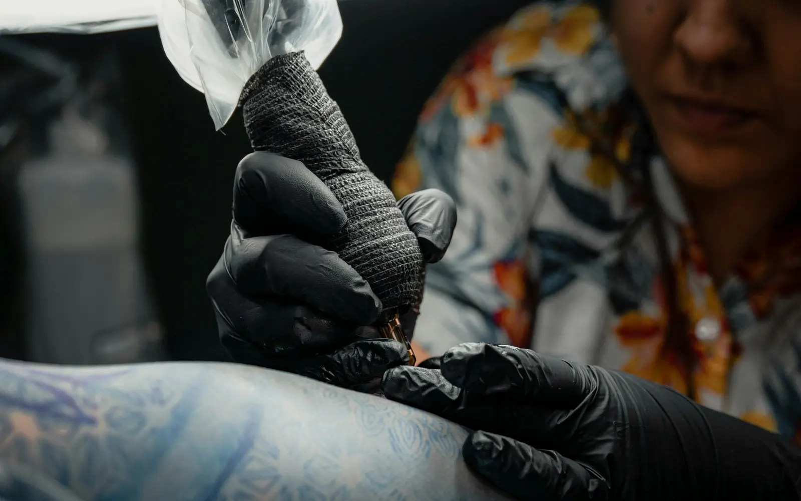 Tattoo artist applying illustrative tattoo to a woman